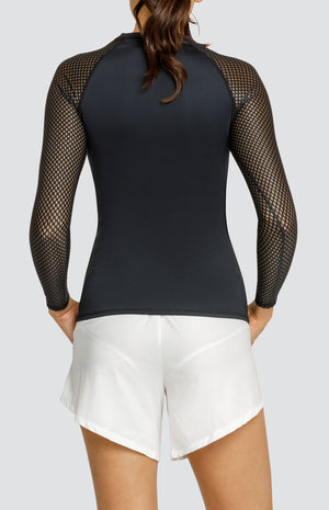 Model wearing a black crew neck shirt with raglan sleeves in a diamond mesh fabric and white shorts with elastic waistband and pockets.