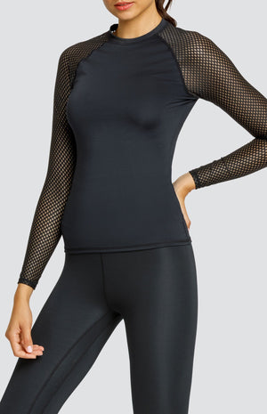 Model wearing a black crew neck shirt with raglan sleeves in a diamond mesh fabric and black high waisted leggings.