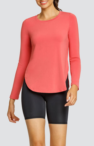 Model wearing a coral long sleeve top with a curved hem and high side slits, and black biker shorts.