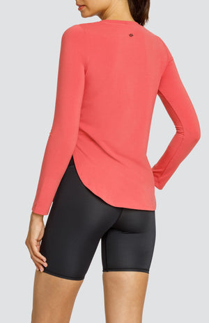 Model wearing a coral long sleeve top with a curved hem and high side slits, and black biker shorts.