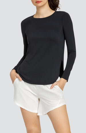 Model wearing a long sleeve top with high side slits and white shorts with elastic waistband and pockets.