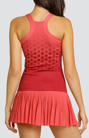 Model wearing a high neck tank top in a coral hexagonal print, and a coral micro pleated skort.