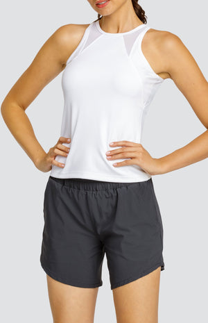 Model wearing a white high neck tank top with mesh inserts and black shorts with an elastic waistband and pockets.