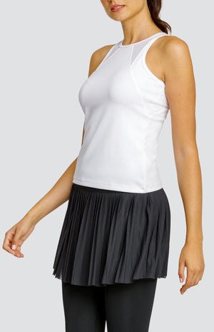 Model wearing a white high neck tank top with mesh inserts and high waisted black leggings with an attached mesh micro pleated skirt.