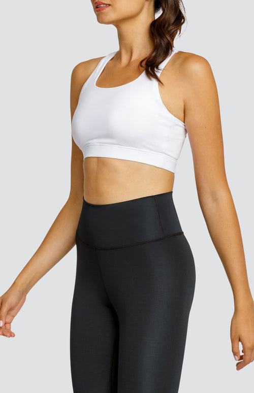 Model wearing a white scoop neck sports bra and black high waisted leggings.