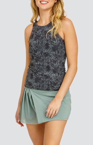 Model wearing a high neck medium support tank top in a snakeskin print, paired with a solid sage green skort with a mesh asymmetrical pleat panel.