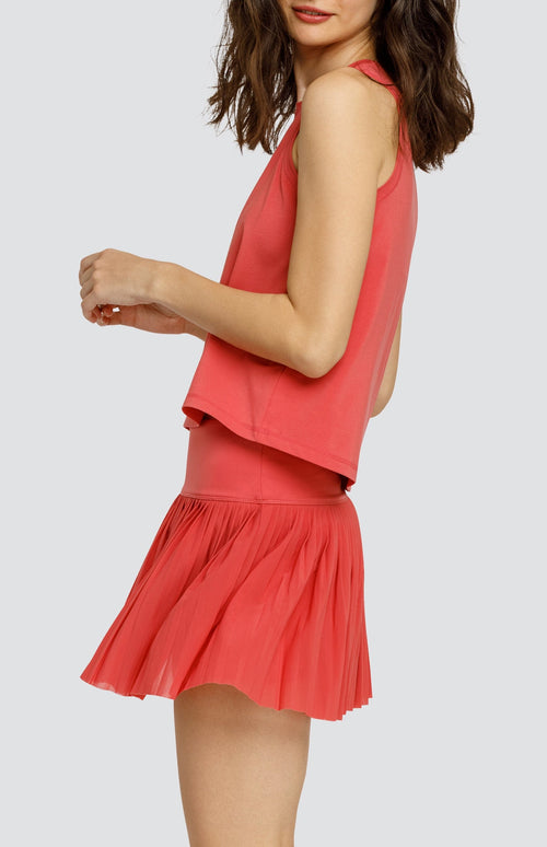 Model wearing coral hi-low swing tank top and coral micro pleated mesh skort.