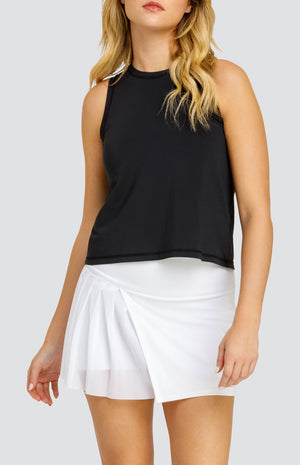 Model wearing a solid black hi-low swing tank top, paired with a solid white skort with a mesh asymmetrical pleat panel.