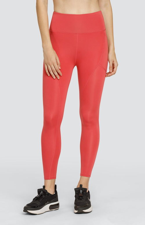 Model wearing coral high rise leggings with side pockets.