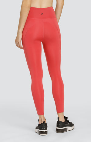 Model wearing coral high rise leggings with side pockets.