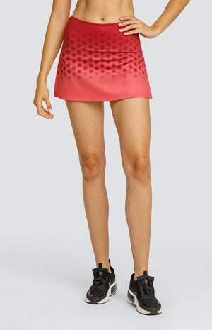 Model wearing a pull on skort with a hexagonal ombre print in coral and a high side slit.