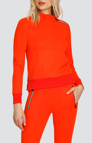 Model is wearing a Red-Orange pullover with side zipper at the collar and a kangaroo pocket. Paired with matching Red-Orange Eleanor joggers. 