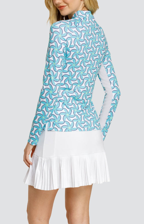 Model wearing a long sleeve top with spiral floral pattern in turquoise and blue on a white background, and a solid white skort.