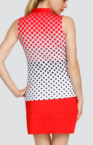 Model wearing a sleeveless golf top with a diamond ombre print, and a red skort.