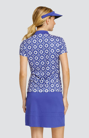 Model wearing a short sleeve golf top with a blue and white geometric pattern, and a solid blue golf skort and visor.