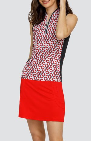 Model wearing a sleeveless golf top with a red and white geometric print, and a red skort.