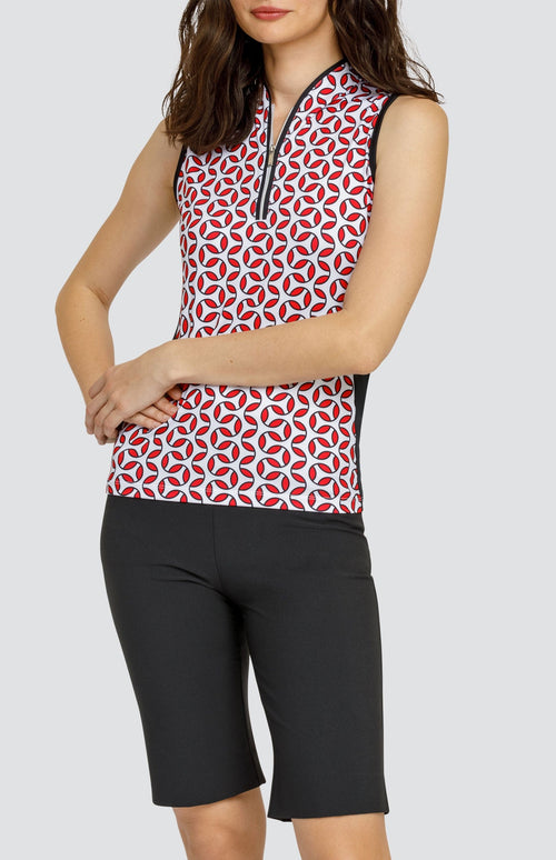 Model wearing a sleeveless golf top with a red and white geometric print, and black shorts.