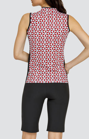 Model wearing a sleeveless golf top with a red and white geometric print, and black shorts.