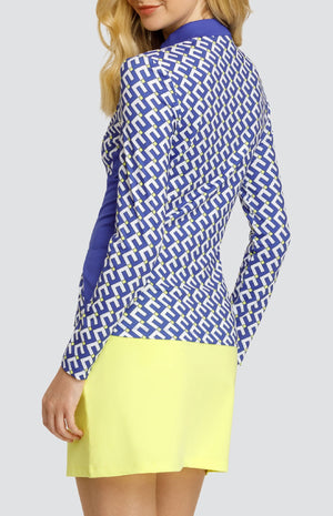 Model wearing a long sleeve golf top with a geometric pattern in blue, white, and yellow with blue side inserts, and a solid yellow pull-on golf skort.