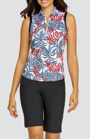 Model wearing a sleeveless golf top with a red and blue palm frond print on a white background, and black shorts.