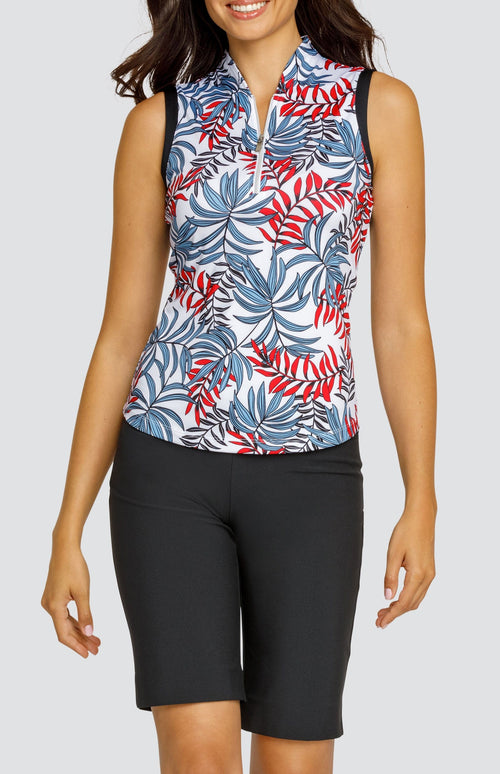 Model wearing a sleeveless golf top with a red and blue palm frond print on a white background, and black shorts.