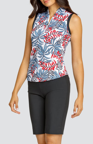 Model wearing a sleeveless golf top with a red and blue palm frond print on a white background, and black shorts.