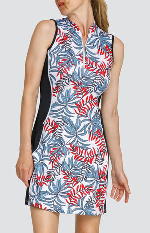 Model wearing a sleeveless golf dress with a red and blue palm frond print on a white background with black side inserts.