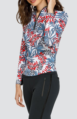 Model wearing a long sleeve golf top with red and blue fronds on a white background, and black pants.