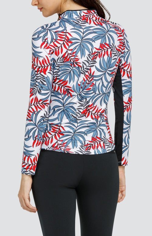 Model wearing a long sleeve golf top with red and blue fronds on a white background, and black pants.