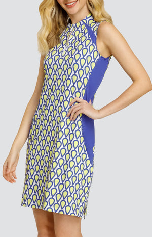 Model wearing a sleeveless golf dress with a teardrop pattern in yellow, blue, and white with blue inserts.