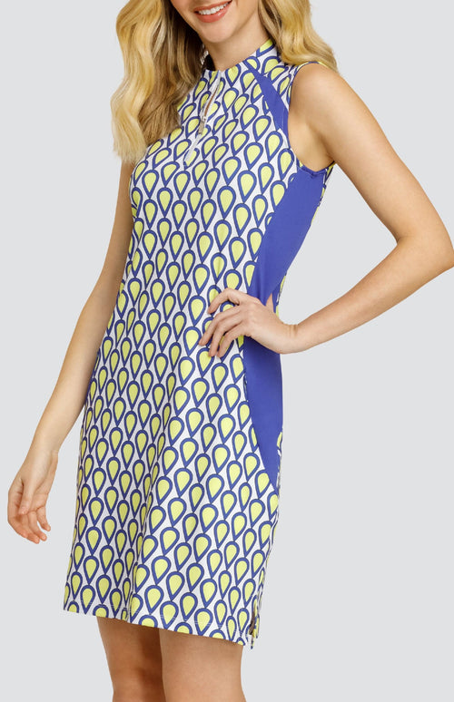 Model wearing a sleeveless golf dress with a teardrop pattern in yellow, blue, and white with blue inserts.