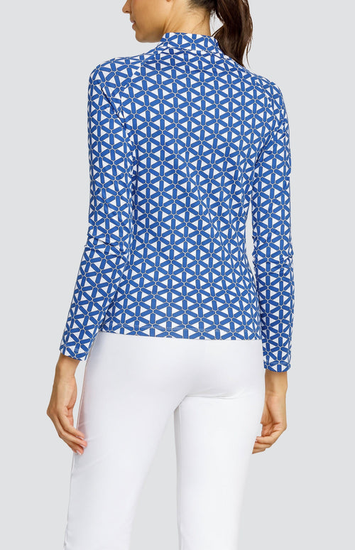 Model wearing a long sleeve golf top with a blue and white lattice pattern, and white pants.