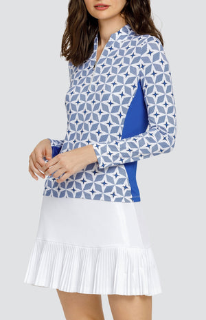 Model wearing a long sleeve golf top with a starry blue and white print and solid blue side inserts, and a solid white skort.