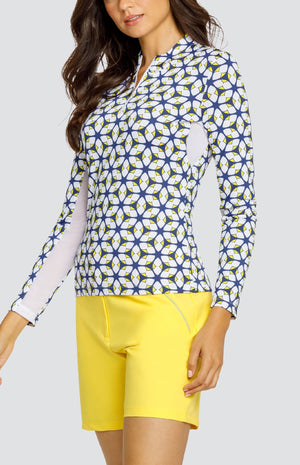 Model is wearing a long-sleeved performance jersey top in "Nova Rush" pattern. The top has Lakestorm Blue, Chalk White, and Dandelion yellow. Top has a novelty collar with a front quarter zip detailing. 