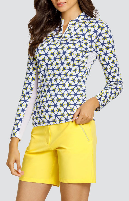 Model is wearing a long-sleeved performance jersey top in "Nova Rush" pattern. The top has Lakestorm Blue, Chalk White, and Dandelion yellow. Top has a novelty collar with a front quarter zip detailing. 