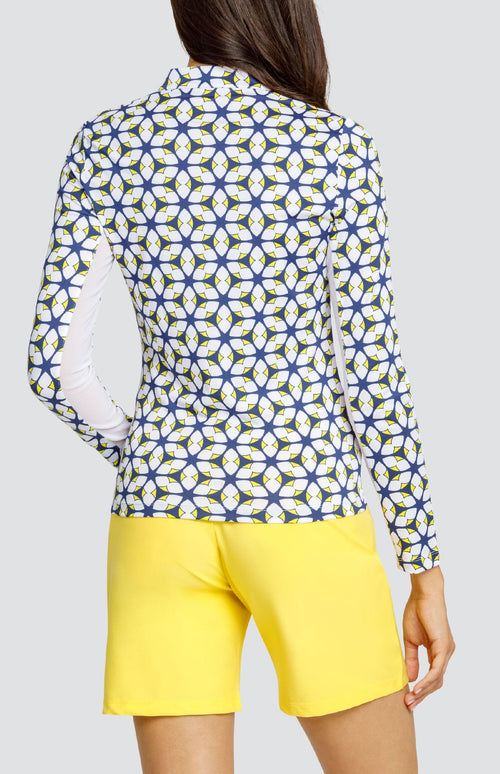 Model is wearing a long-sleeved performance jersey top in "Nova Rush" pattern. The top has Lakestorm Blue, Chalk White, and Dandelion yellow. Top has a novelty collar with a front quarter zip detailing. 