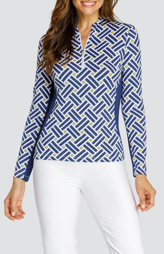 Model wearing a long sleeve quarter zip gold top with a blue criss cross pattern and yellow squares on a white background, with solid white pull on pants.