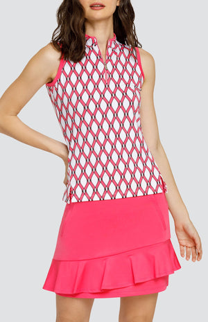 Model wearing a sleeveless quarter-zip golf top with a pink and white lattice pattern, and a pull on pink golf skort with a flounce hem.