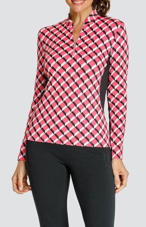 Model wearing a long sleeve quarter-zip golf top with a pink 3-dimensional block pattern and pull on black golf pants.