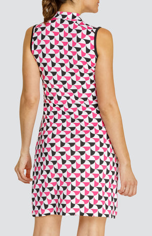 Model wearing a sleeveless quarter-zip golf dress in a pink and black alternating triangular print on a white background with black side inserts.