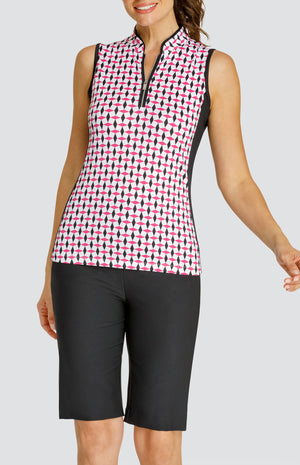 Model wearing a sleeveless quarter-zip golf top in a pink and black geometric alternating diamond print on a white background with black side inserts, paired with solid black pull-on golf shorts.