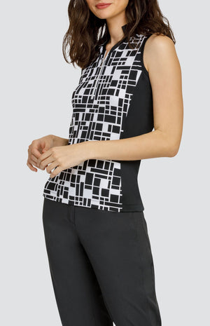 Model wearing a sleeveless black and white geometric pattern golf top and black pants.