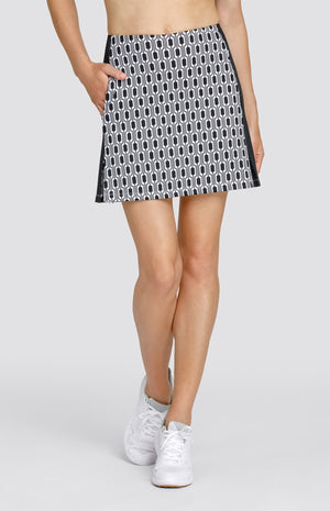 Model wearing a pull-on golf skort with a black and white chain link pattern with black inserts.