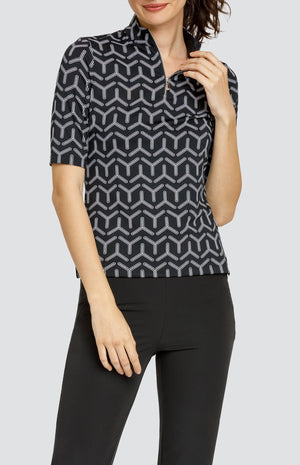 Model wearing a mid sleeve golf top with a black and white geometric print, and black pants.